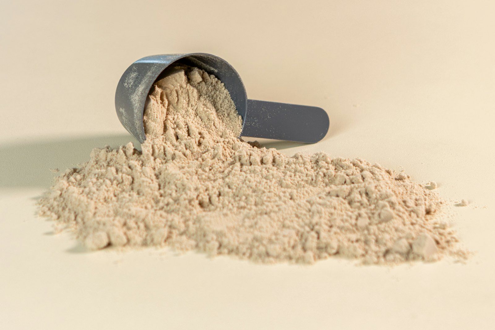 A scoop of pale powder spilling onto a warm beige surface